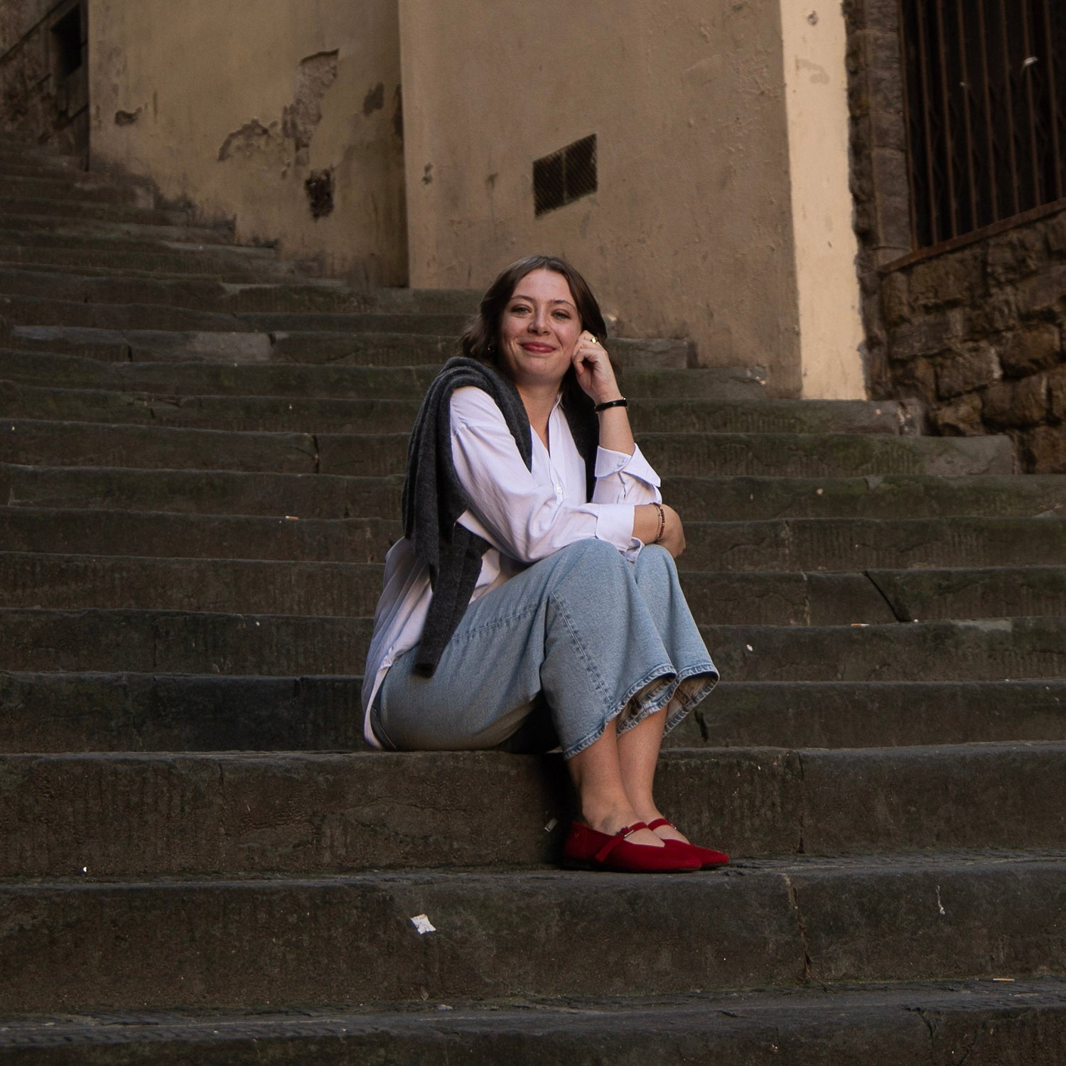 Woman sitting on stone steps in an urban setting