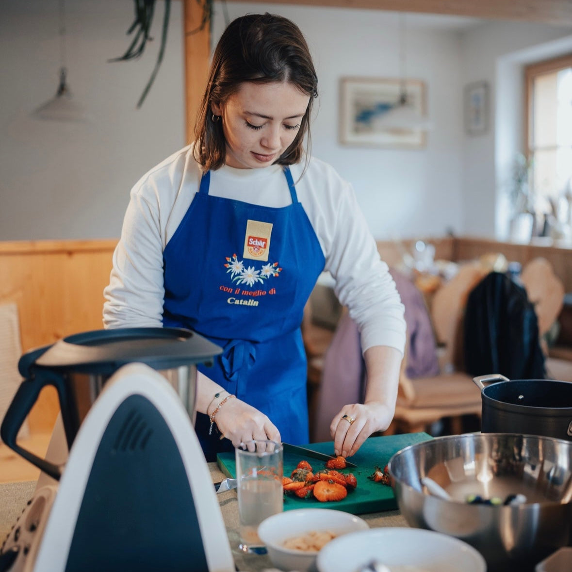 Woman in a blue apron preparing food in a kitchen