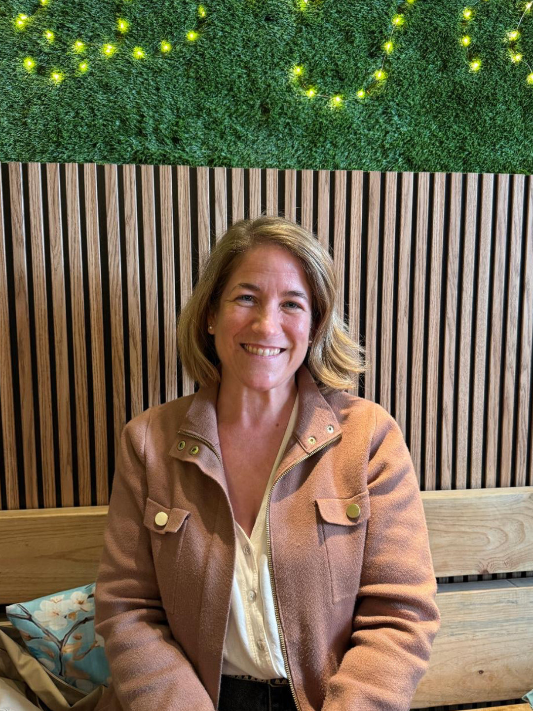 Woman sitting on a bench with a green wall and wooden paneling in the background