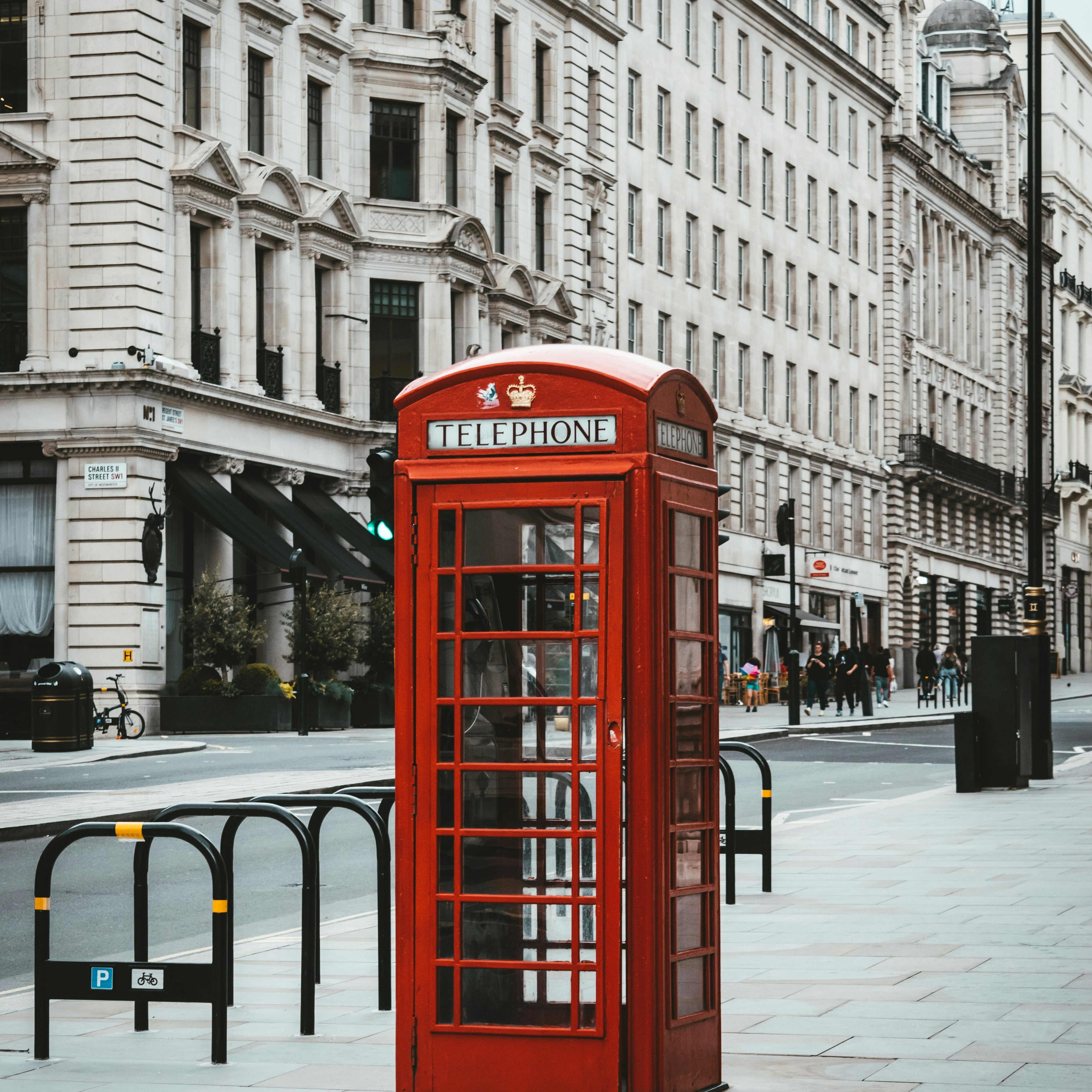 Red telephone booth on a city street with tall buildings in the background